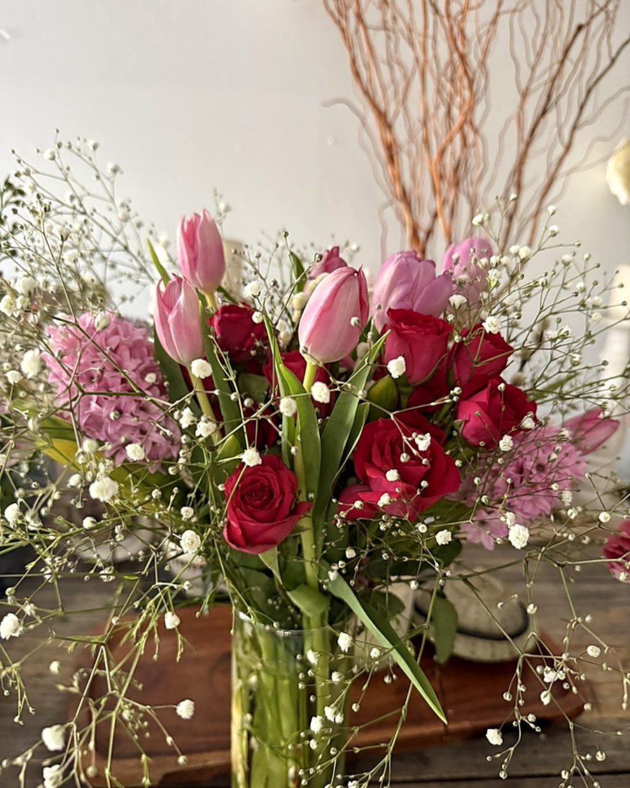 Bouquet of pink tulips, red garden roses, pink hyacinth and baby&rsquo;s breath in a glass vase
