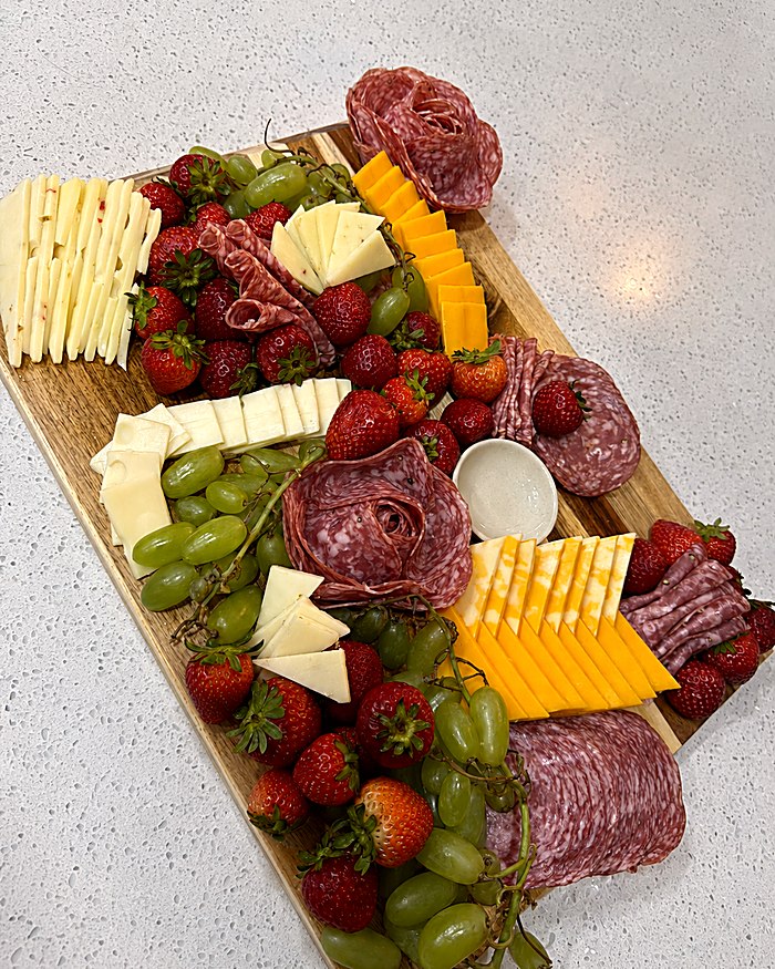 Charcuterie board with cured meats, cheeses, strawberries and grapes